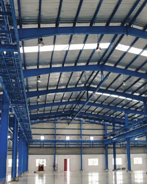 Interior of the ABB India RBIKC plant shed at Halol with blue steel portal frames and skylights