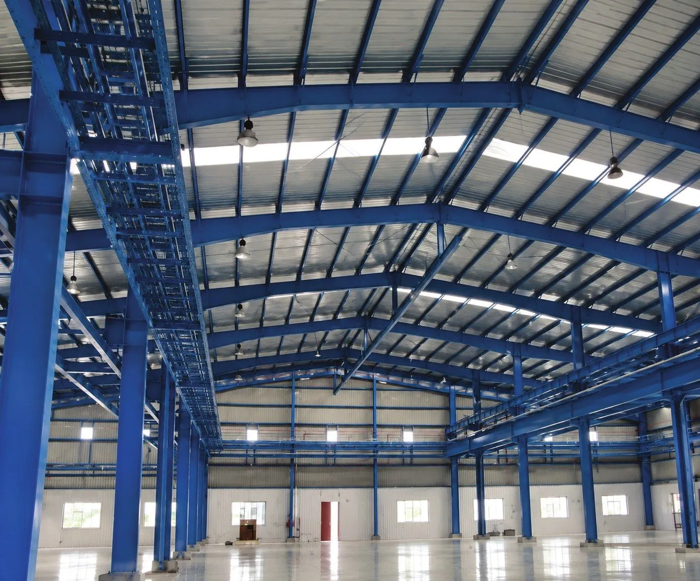 Interior of the ABB India RBIKC plant shed at Halol with blue steel portal frames and skylights