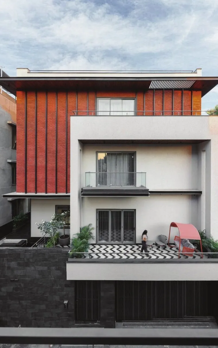 White residence with a terracotta-finned upper floor and planted terrace