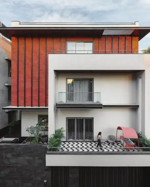 White residence with a terracotta-finned upper floor and planted terrace