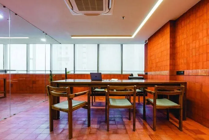 Conference room with terracotta tile wall, timber table and linear lighting